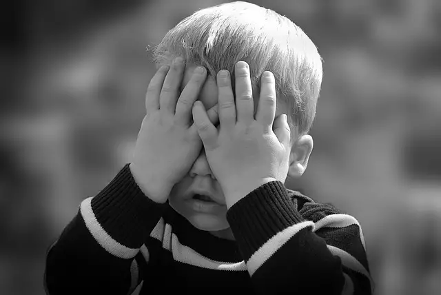 child hiding his face with his hands