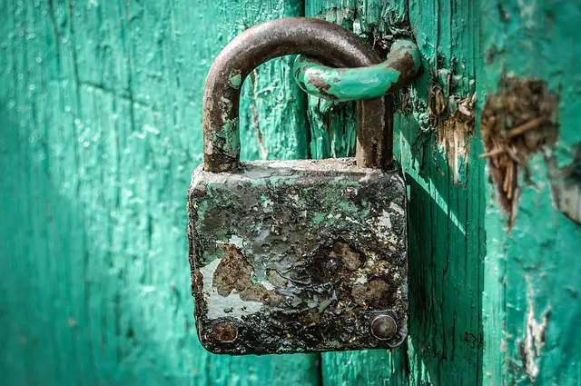 An old rusty padlock attached on a rough wood