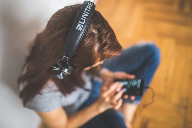 A woman sitting on the ground and listening to music with her heaphones on