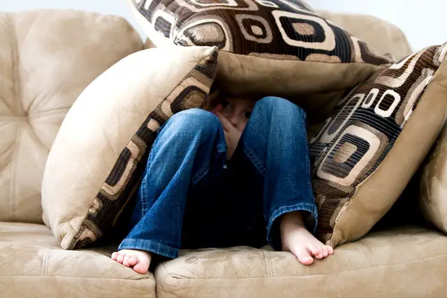 child hiding behnd cushions